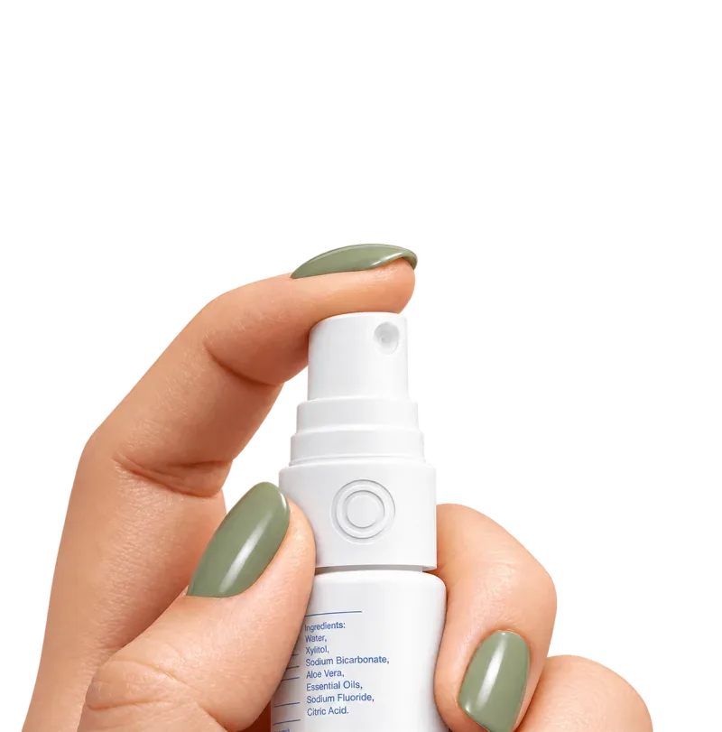 Hand pressing a white oral spray bottle with an embossed double-ring logo